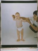 Baby in diaper, standing up with Mom's help